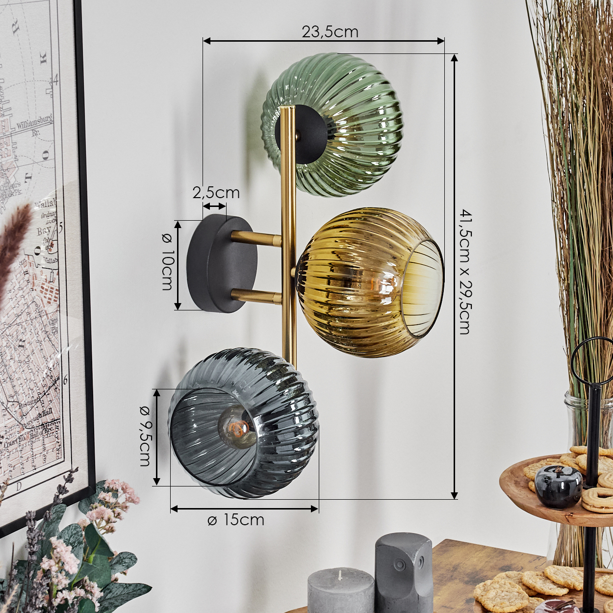 Eine Wandlampe mit drei Glaskugeln in Grün, Gold und Grau. Abmessungen sind angegeben. Hintergrund: Karte, Blumen und Kekse.