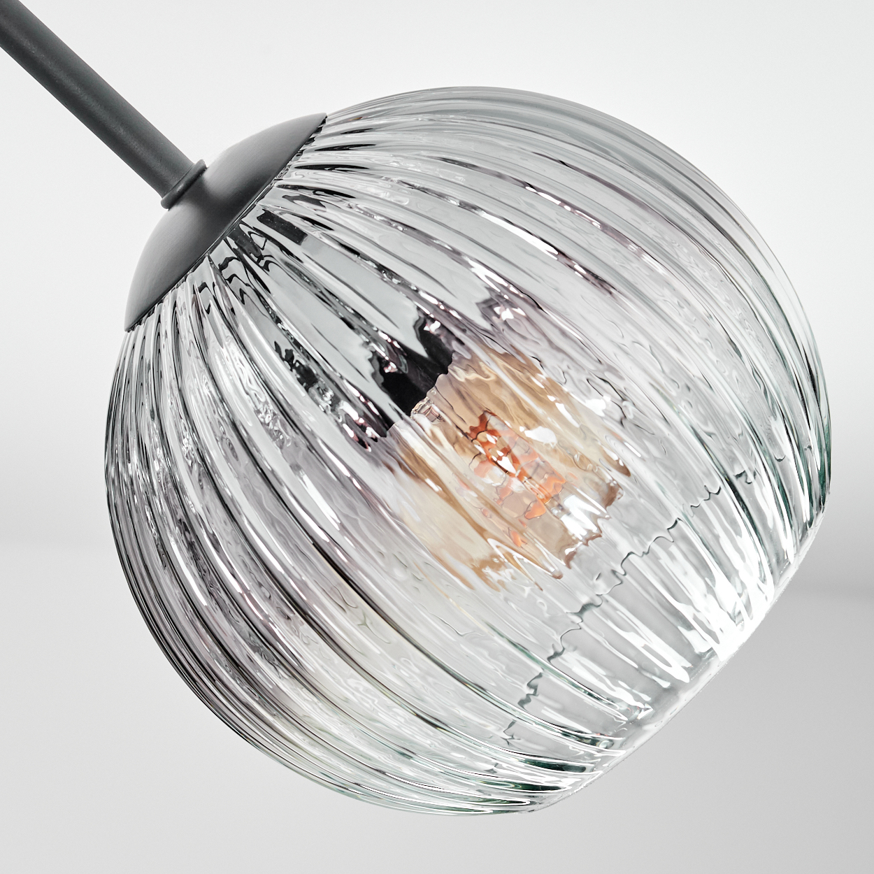 Eine klare, gerippte Glas-Pendelleuchte mit sichtbarer Glühbirne. Die Leuchte ist an einer grauen Stange vor weißem Hintergrund befestigt.