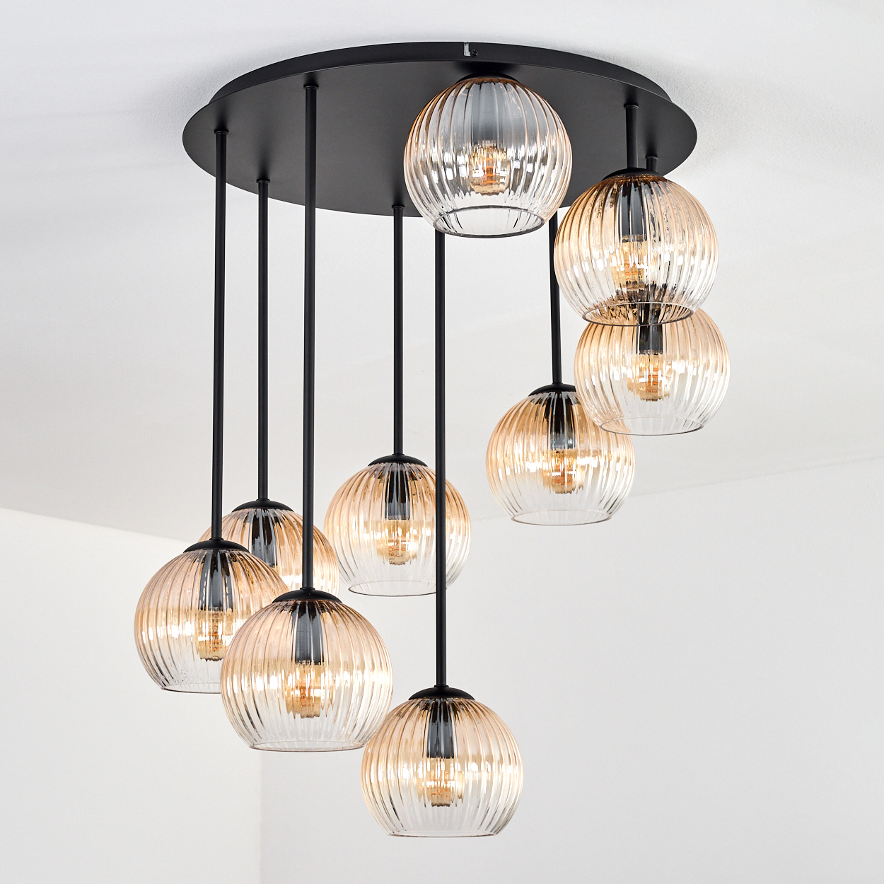 Ein moderner Kronleuchter mit mehreren kugelförmigen Lichtern, die von einer schwarzen runden Basis hängen. Die Kugeln sind bernsteinfarbenes Glas.