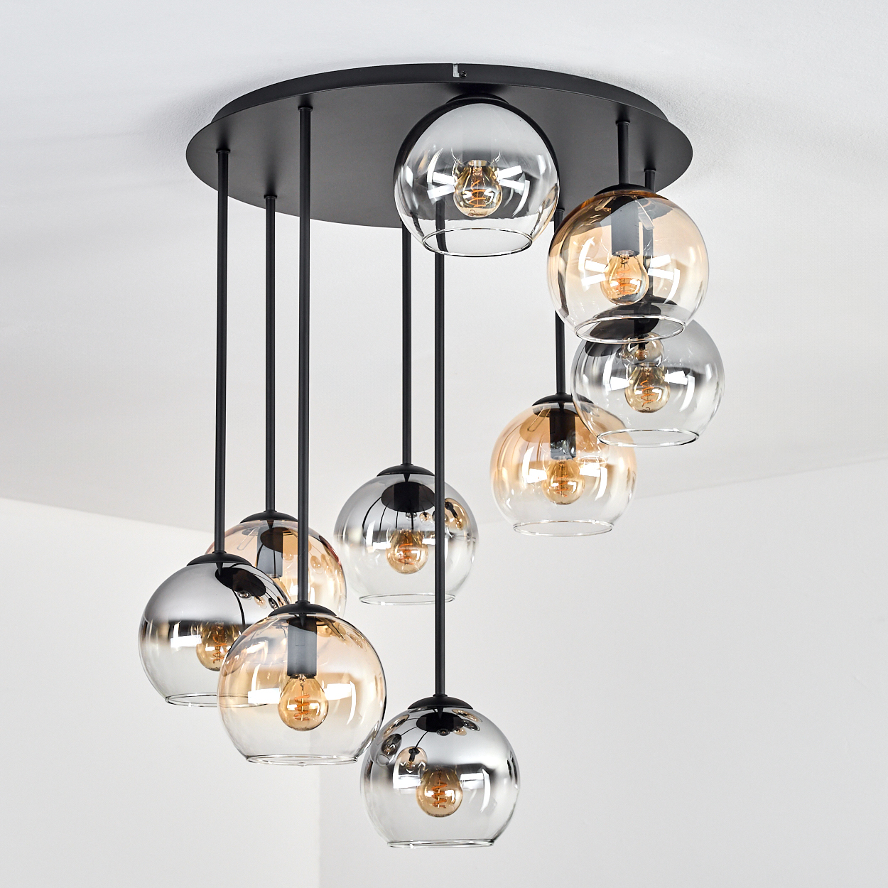 Eine moderne Deckenleuchte mit mehreren kugelförmigen Glaslampen, die von einer schwarzen runden Basis hängen. Die Lampen haben klare und bernsteinfarbene Farbtöne.