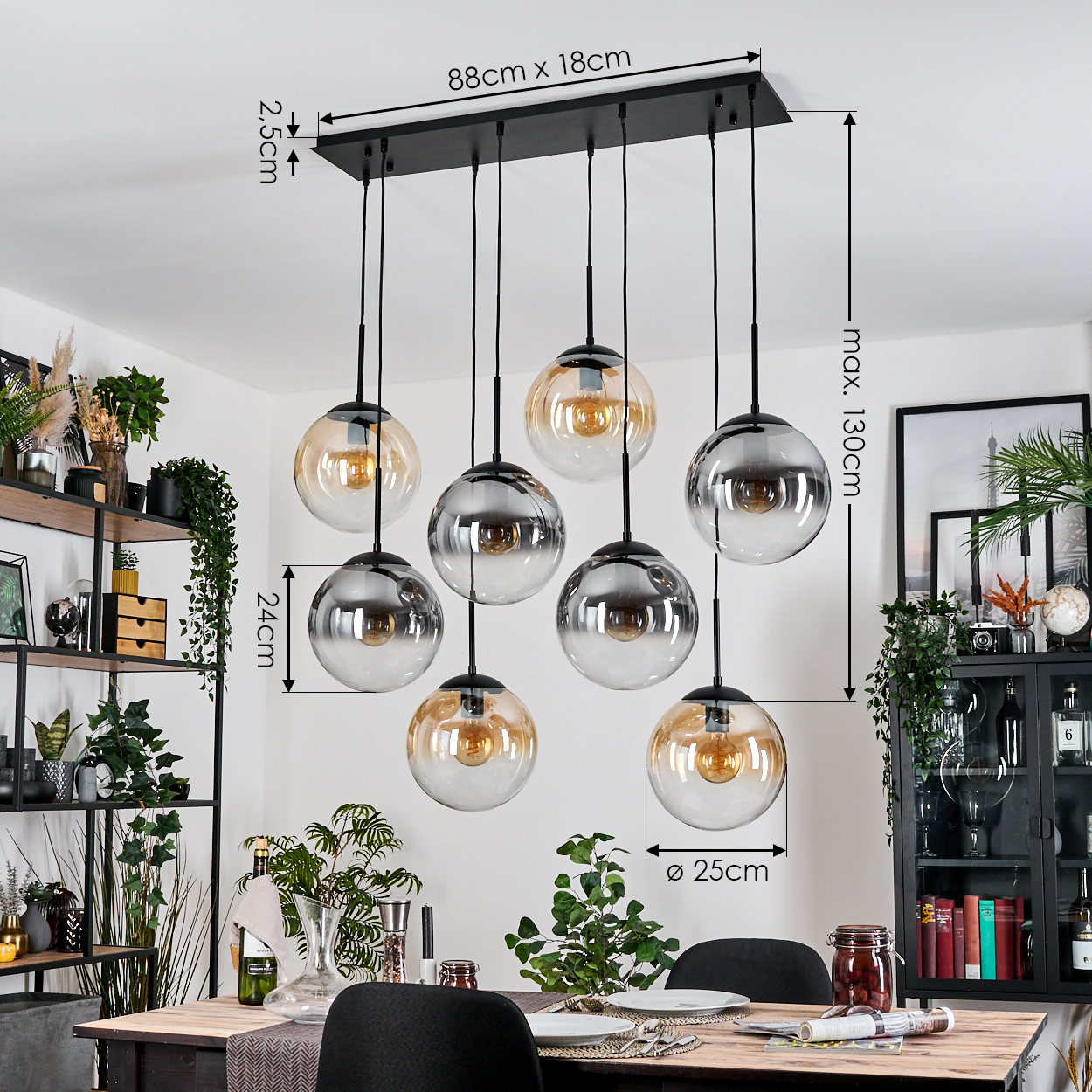 Ein modernes Esszimmer mit einem schwarzen Kronleuchter mit acht Kugelleuchten. Ein Holztisch ist mit Tellern und Gläsern gedeckt. Pflanzen und Dekoration sind vorhanden.