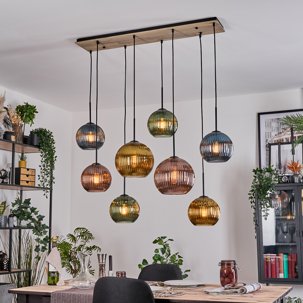 Ein Esszimmer mit Holztisch, Stühlen und mehreren farbigen Glaskugel-Hängelampen, die von der Decke hängen.