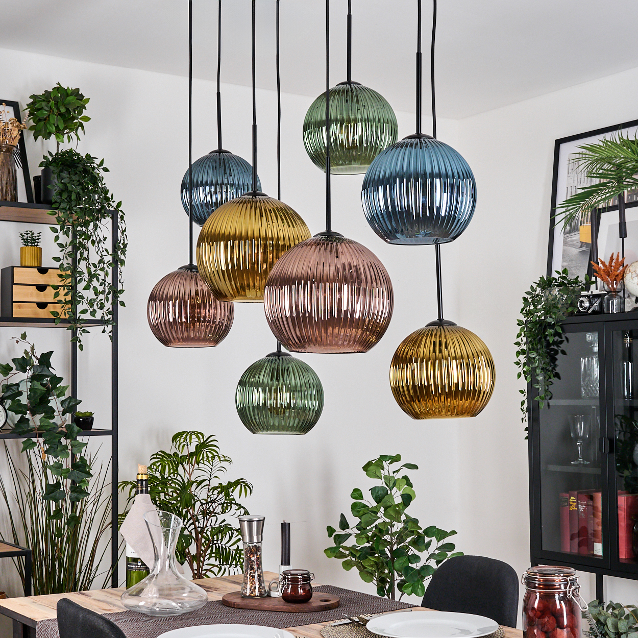 Esszimmer mit bunten Kugelleuchten. Pflanzen und Esstisch mit Dekoration im Vordergrund.
