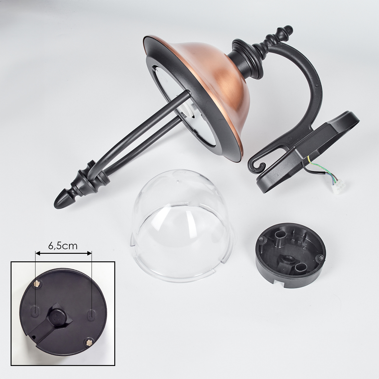 Zerlegte Außenlampe mit kupferfarbenem Schirm, schwarzem Rahmen, klarer Kuppel und Basiskomponenten, auf weißer Oberfläche.