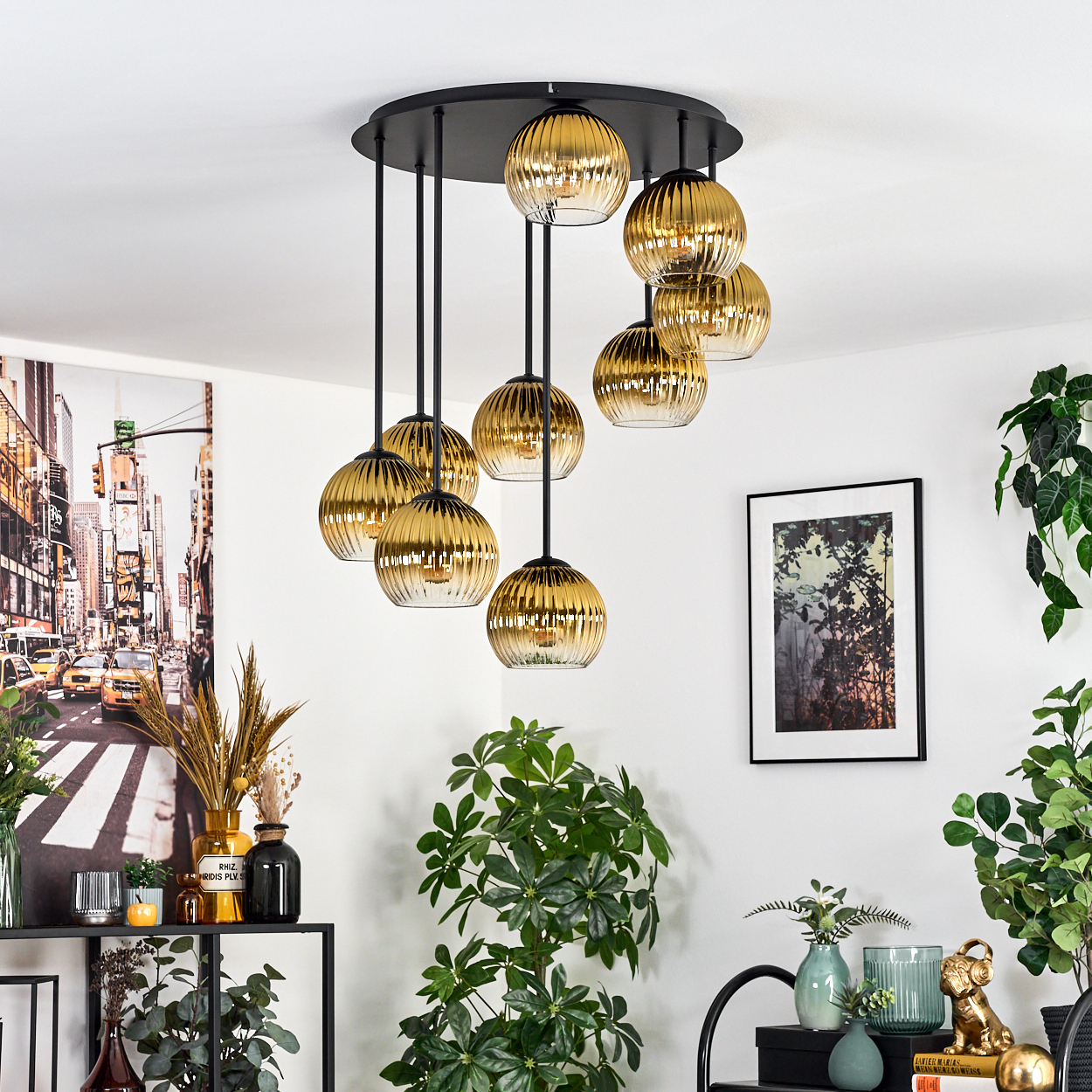 Ein modernes Wohnzimmer mit einem schwarzen und goldenen Kronleuchter. Pflanzen und gerahmte Kunst schmücken die weißen Wände.