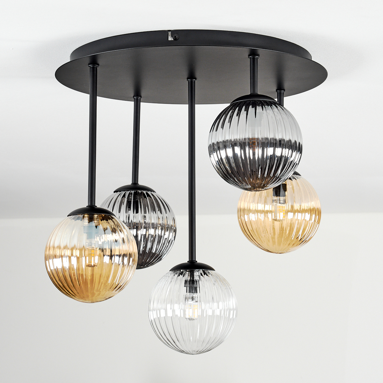 Deckenleuchte mit fünf hängenden, kugelförmigen Glaslampen. Lampen haben geripptes Glas und unterschiedliche Farben, befestigt an einer schwarzen Basis.