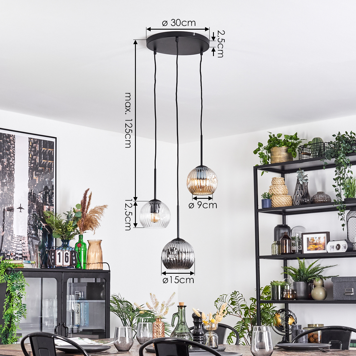 Drei Pendelleuchten hängen über einem Esstisch. Im Hintergrund ein schwarzes Metallregal mit Pflanzen. Abmessungen sind angegeben.