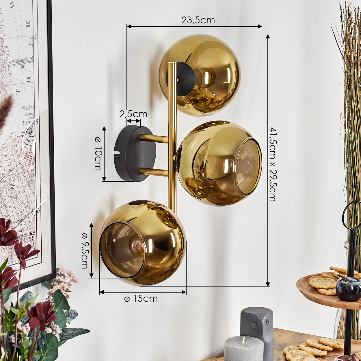 Eine goldene Wandlampe mit drei kugelförmigen Schirmen. Abmessungen sind angegeben. Der Hintergrund umfasst Dekorationen und eine Karte.