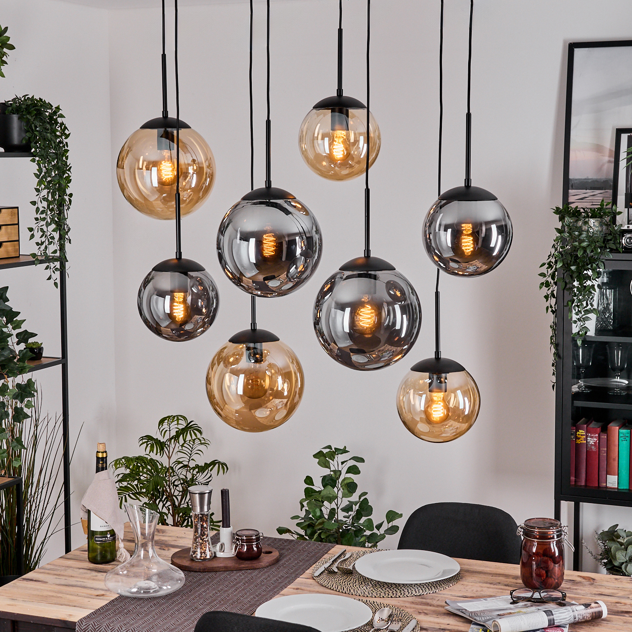 Esszimmer mit Hänge-Kugelleuchten, Holztisch für das Abendessen gedeckt und Pflanzen. Die Lichter sind gold und silber.