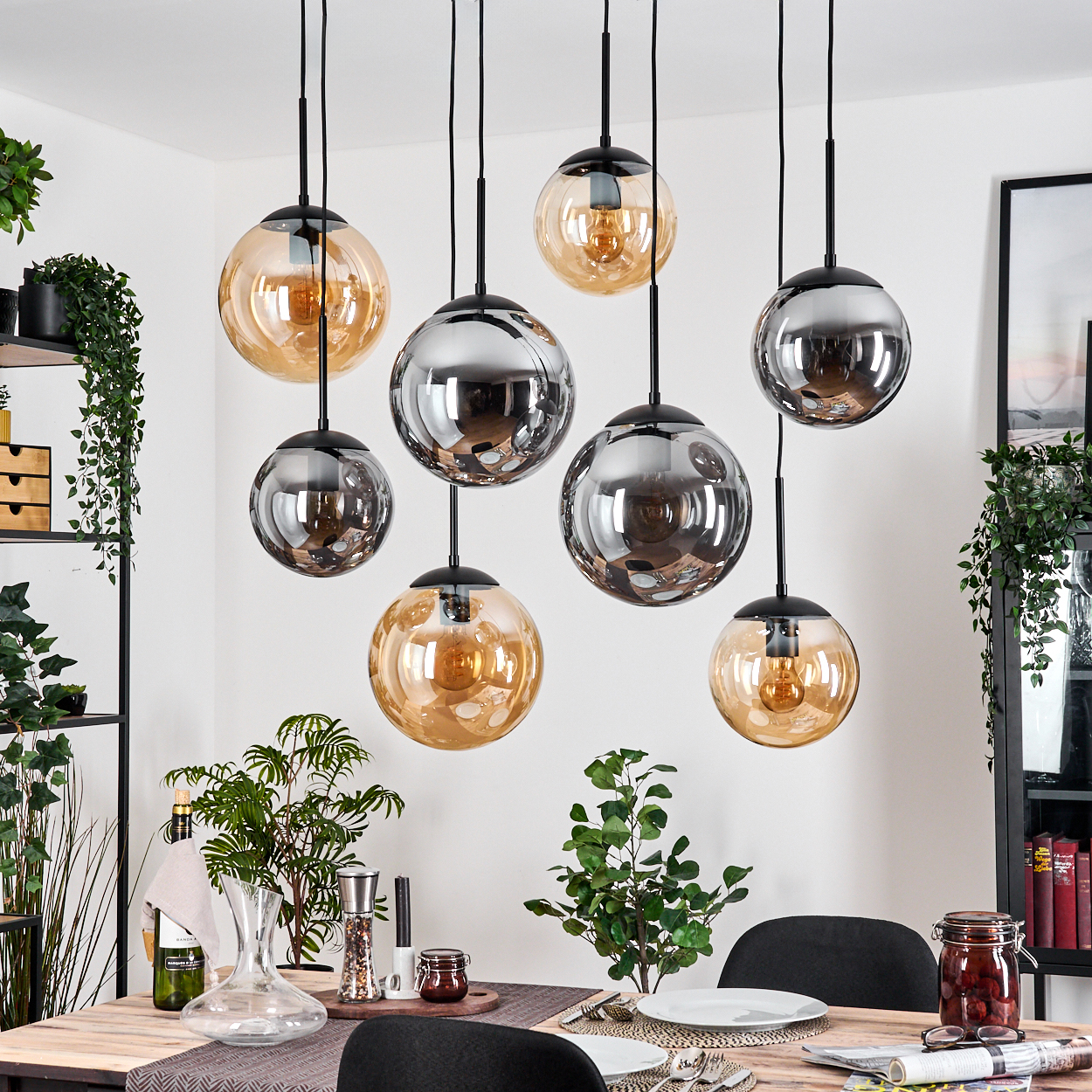 Esszimmer mit hängenden Kugelleuchten, Pflanzen und einem Holztisch, der zum Abendessen gedeckt ist.