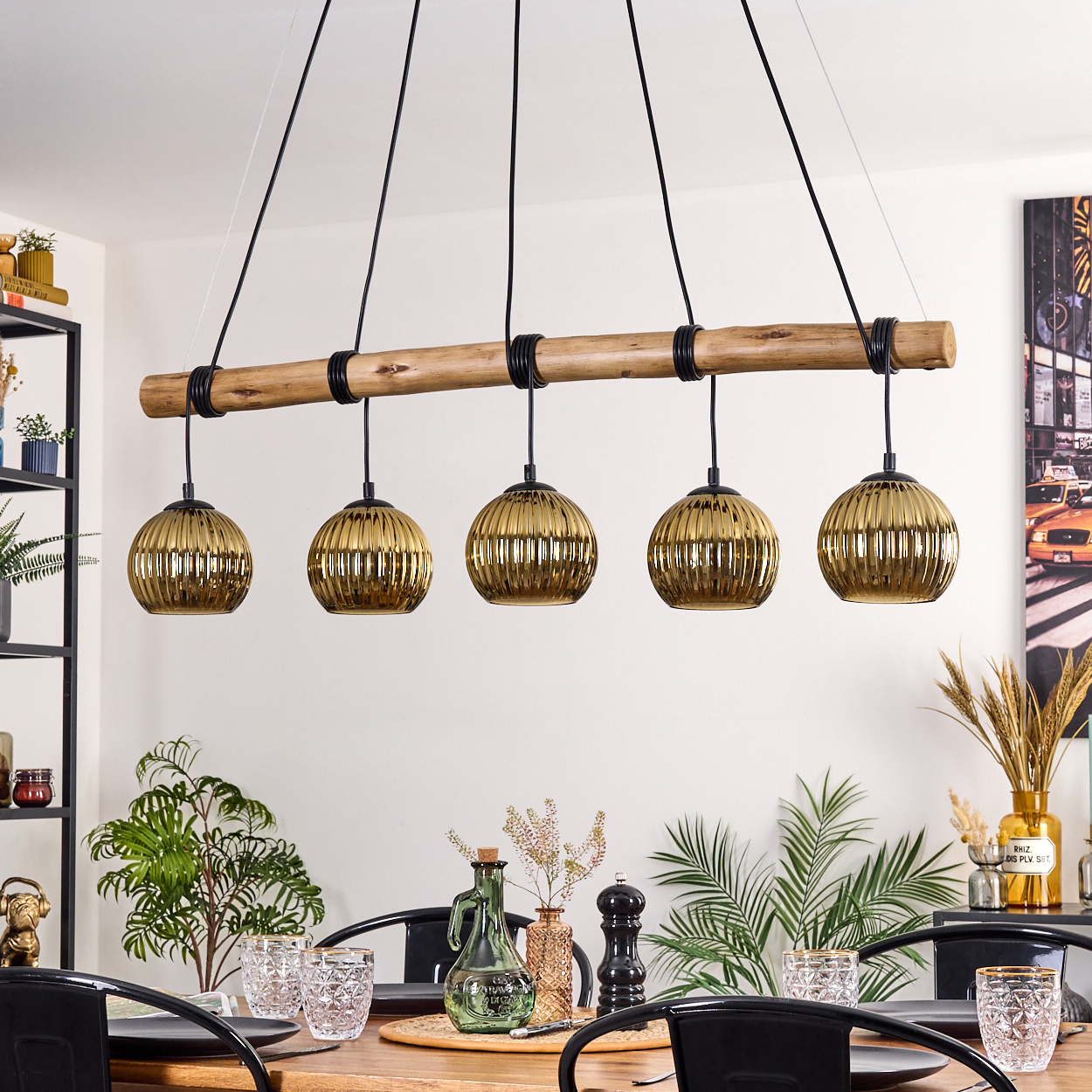 Esszimmer mit Holztisch, schwarzen Stühlen und einer Hängeleuchte mit fünf goldenen Lampenschirmen.