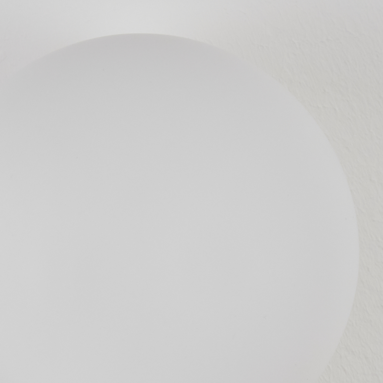 Eine weiße, abgerundete Form vor einem strukturierten weißen Hintergrund. Die Form nimmt den größten Teil des Bildes ein.