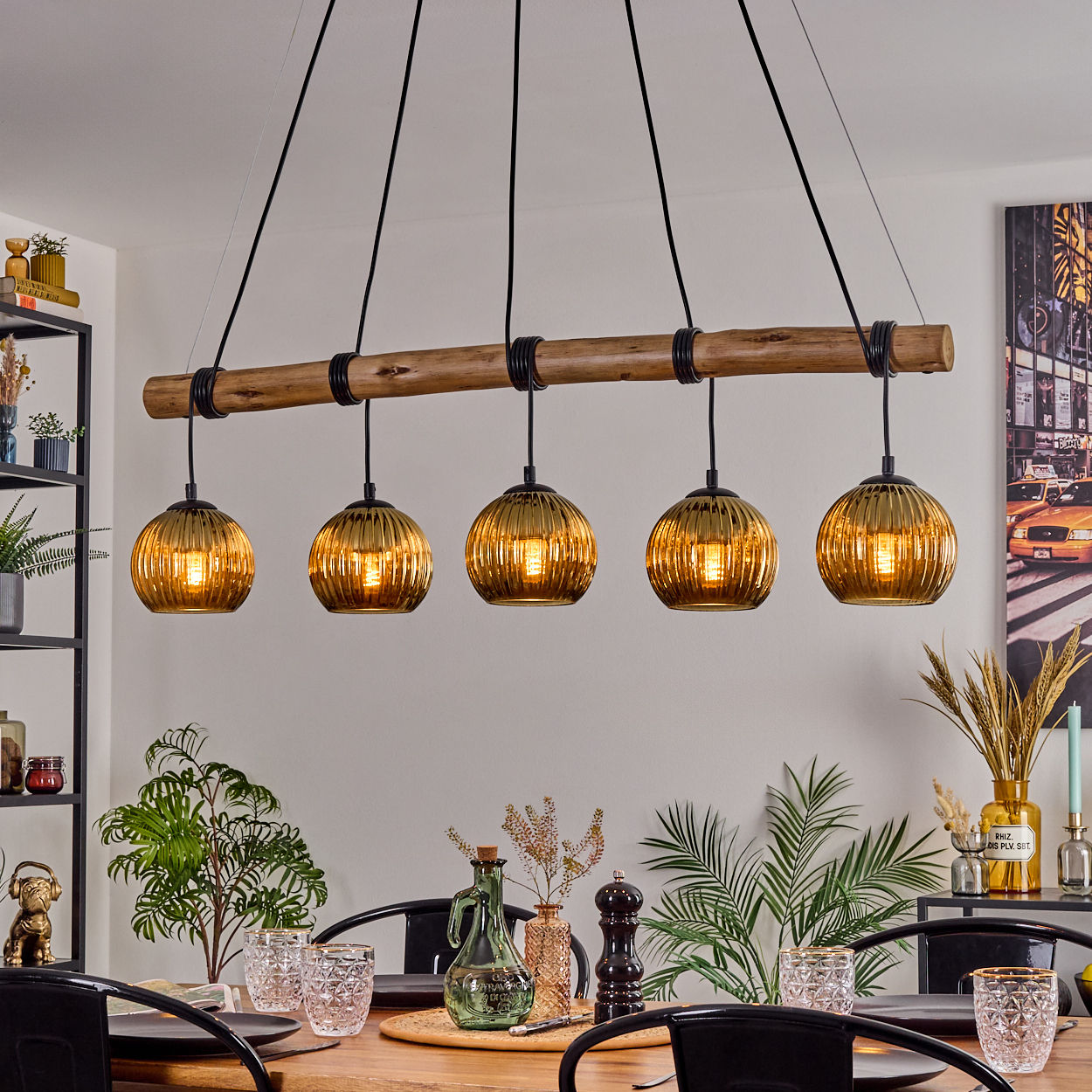Esszimmer mit Holztisch, schwarzen Stühlen und einer Hängeleuchte mit fünf goldenen Kugellampen.