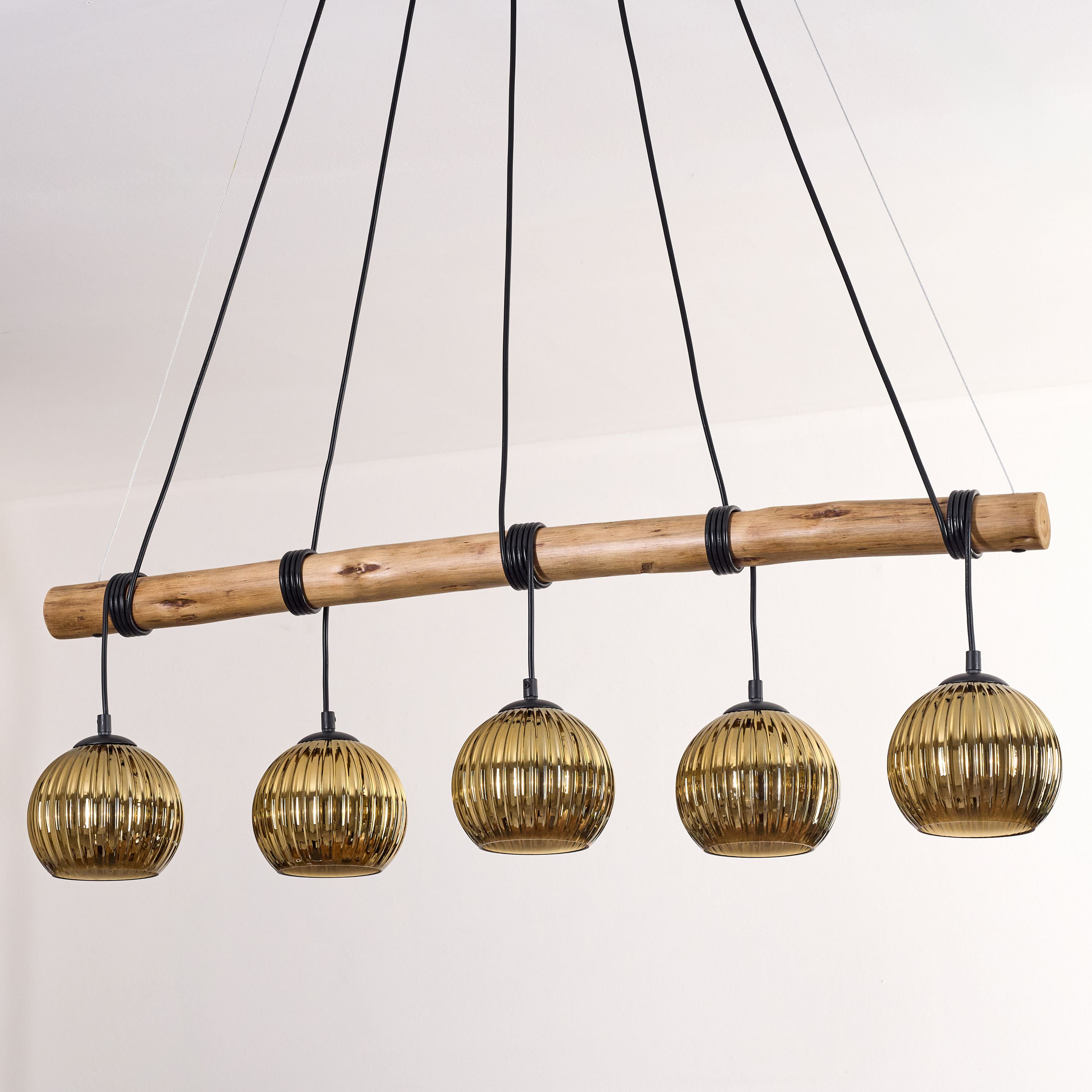 Moderne Deckenlampe mit fünf goldenen Glaslampen, die an einem Holzbalken hängen, schwarze Kabel, weißer Hintergrund.
