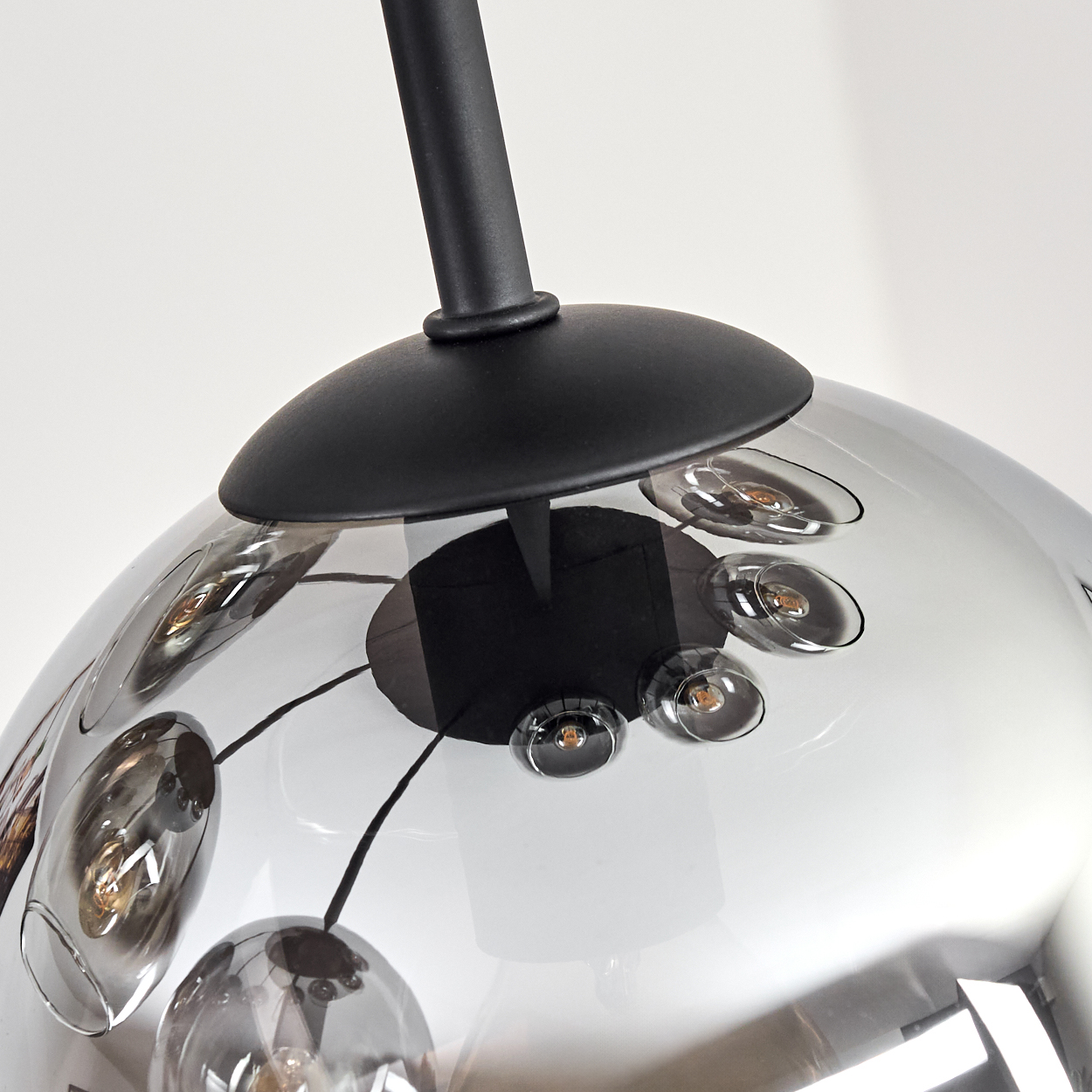 Moderne Pendelleuchte mit schwarzem Stiel und transparentem, blasenartigem Glasschirm mit eingebetteten Lichtern. Weißer Hintergrund.