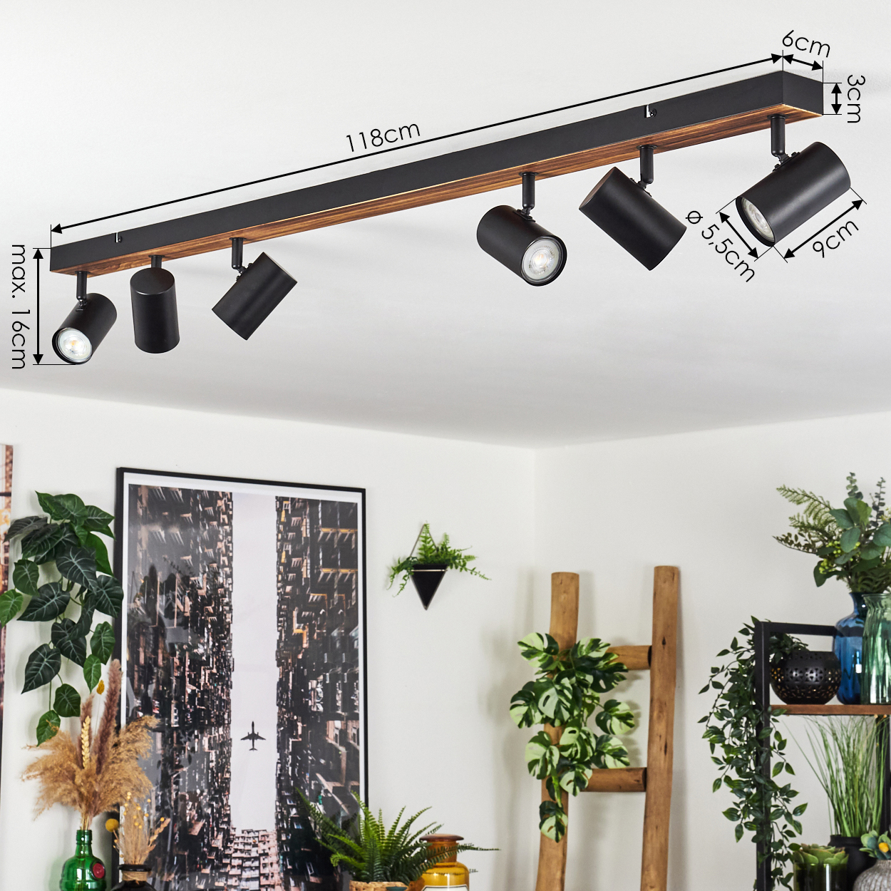An der Decke montierte Schienenbeleuchtung mit Strahlern. Abmessungen sind beschriftet. Der Hintergrund umfasst Pflanzen, Kunstwerke und eine Leiter.