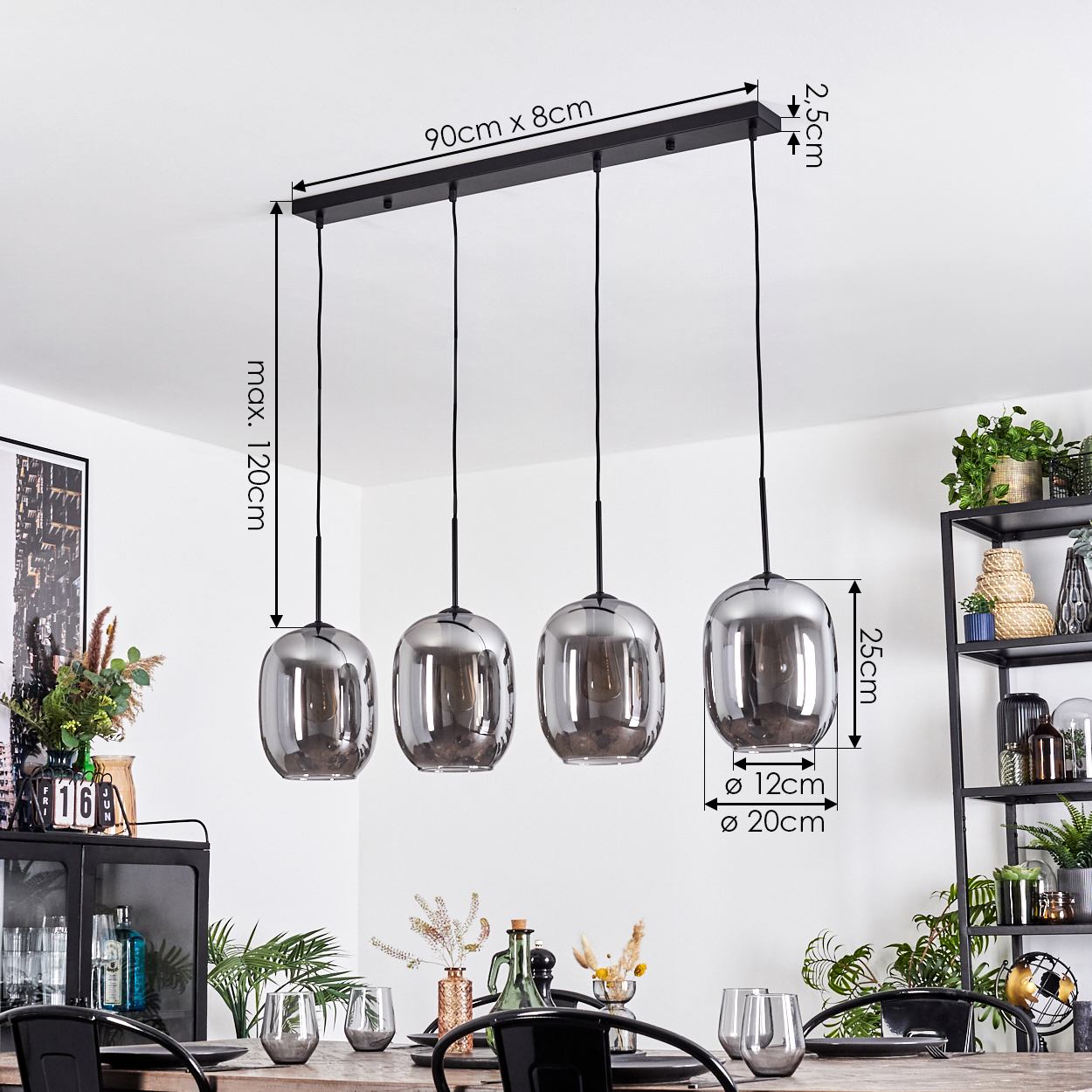 Vier graue Glas-Hängeleuchten hängen von der Decke. Darunter ist ein Tisch gedeckt. Pflanzen und Dekorationen sind im Hintergrund.