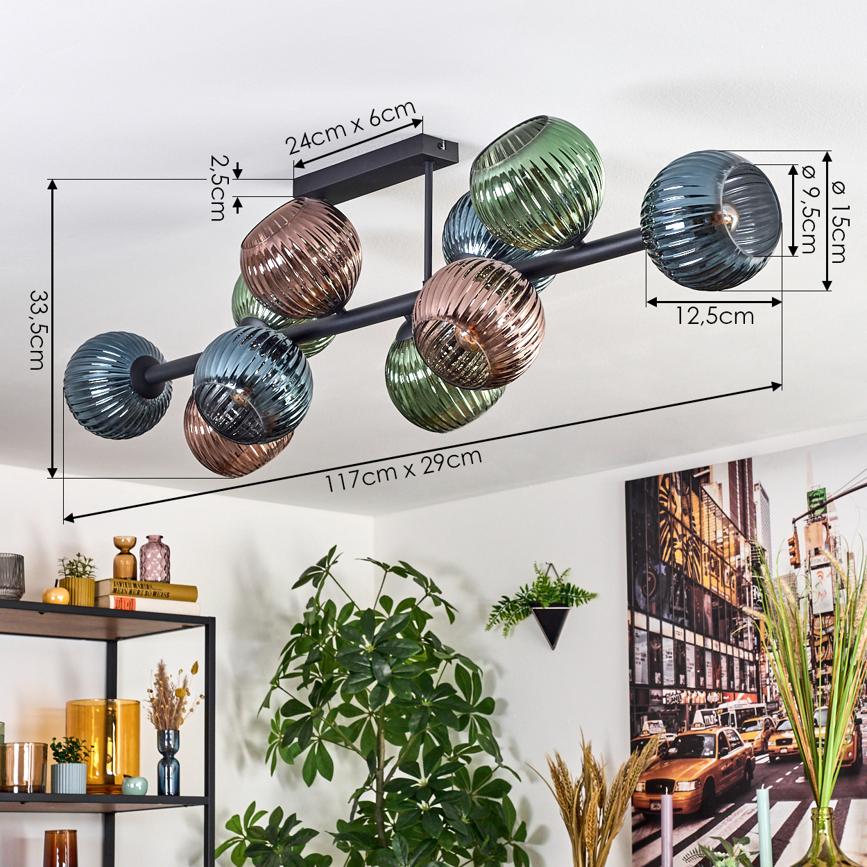 Eine moderne Deckenlampe mit Glaskugeln in verschiedenen Farben. Maße sind angegeben. Ein Bücherregal, Pflanzen und ein Stadtbild sind sichtbar.