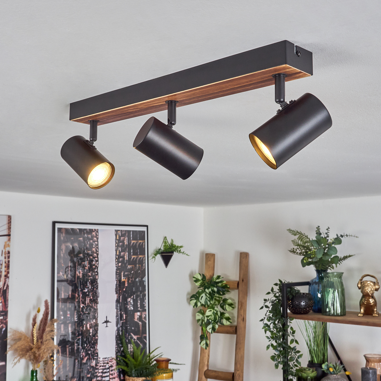 Eine moderne Deckenleuchte mit drei verstellbaren schwarzen Strahlern. Die Leuchte hat ein Holz- und schwarzes Metalldesign.