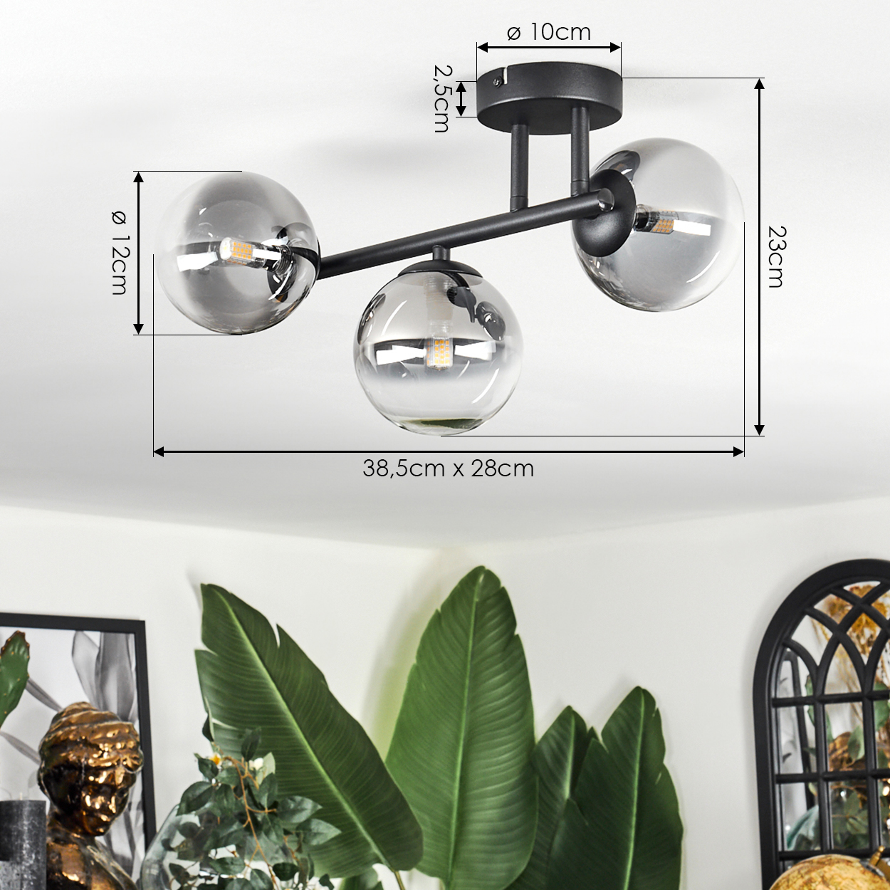 Eine moderne Deckenlampe mit drei Glaskugeln. Darunter große grüne Blätter und ein Teil einer Büste.
