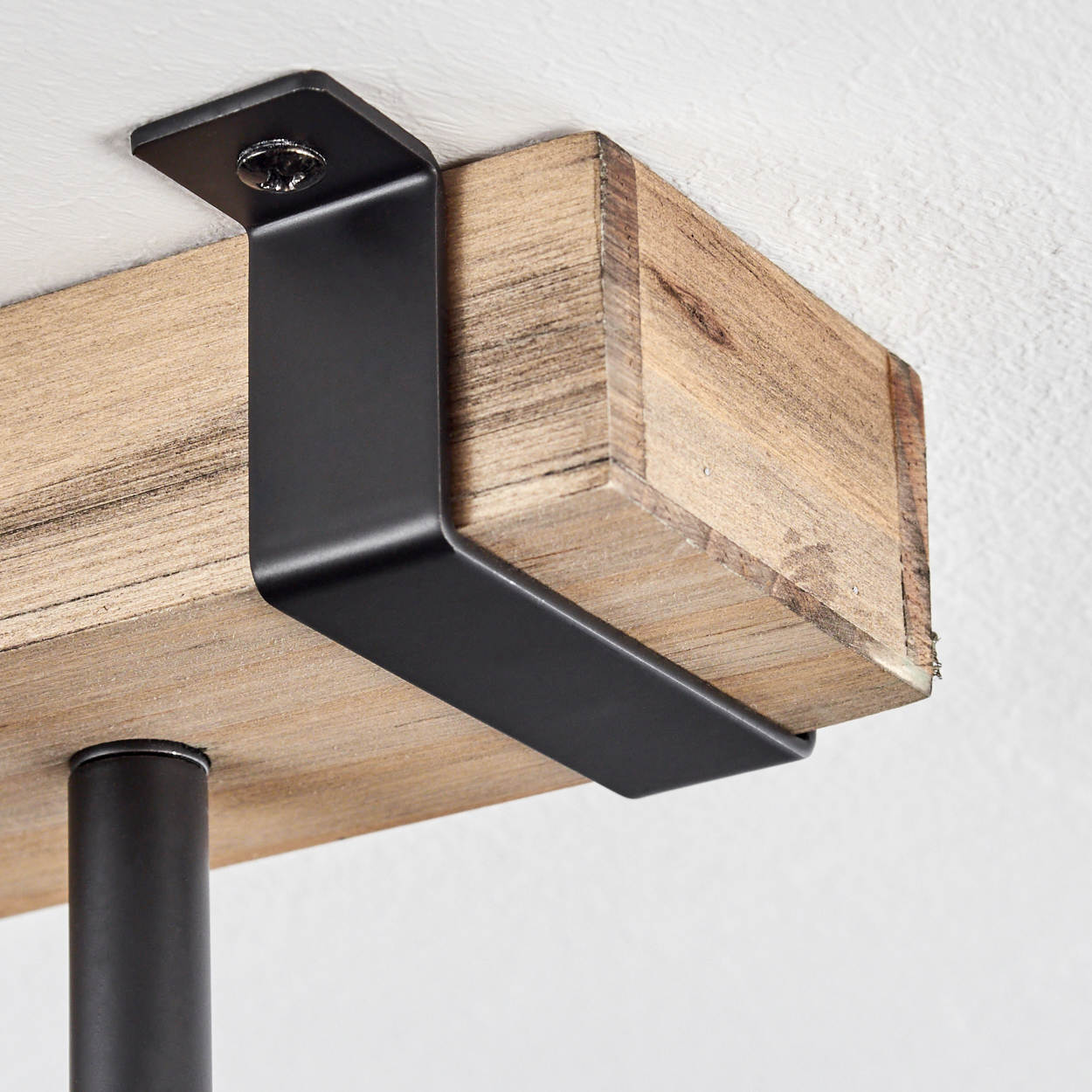 Nahaufnahme eines Holzbalkens, der von einer schwarzen Metallhalterung gehalten wird, die an einer weißen Wand befestigt ist.