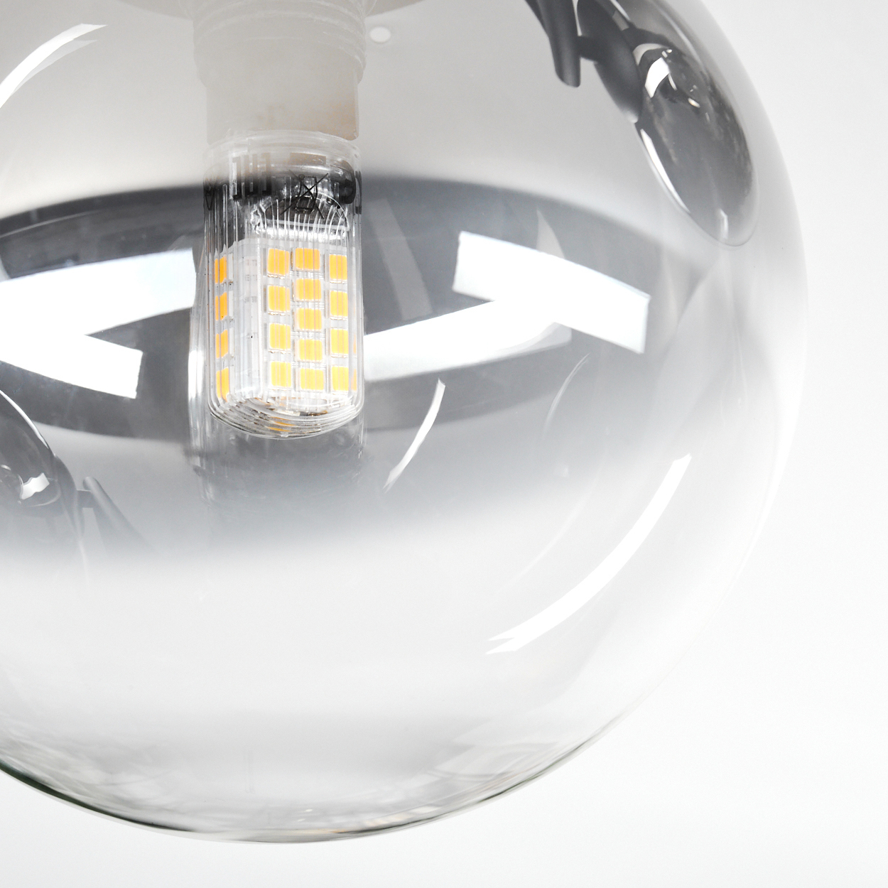Eine klare Glaskugelleuchte. Im Inneren ist eine kleine rechteckige LED-Glühbirne sichtbar. Der Hintergrund ist weiß.