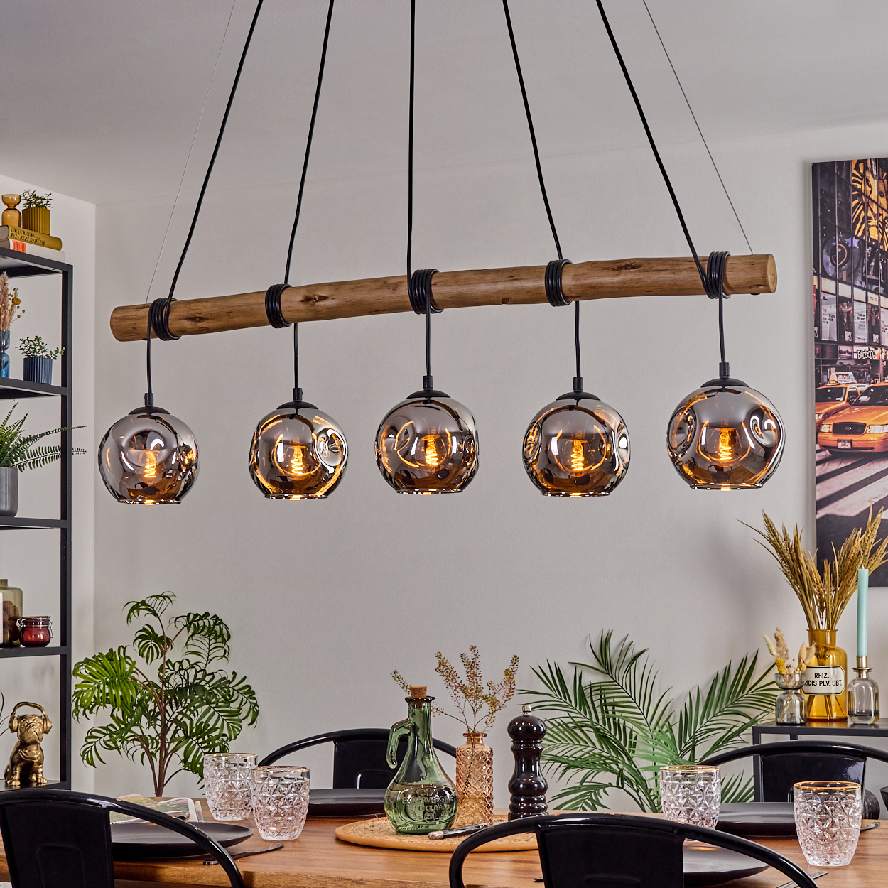 Ein Esszimmer mit Holztisch, Hängelampen und einem Stadtbildgemälde an der Wand. Der Tisch ist zum Abendessen gedeckt.