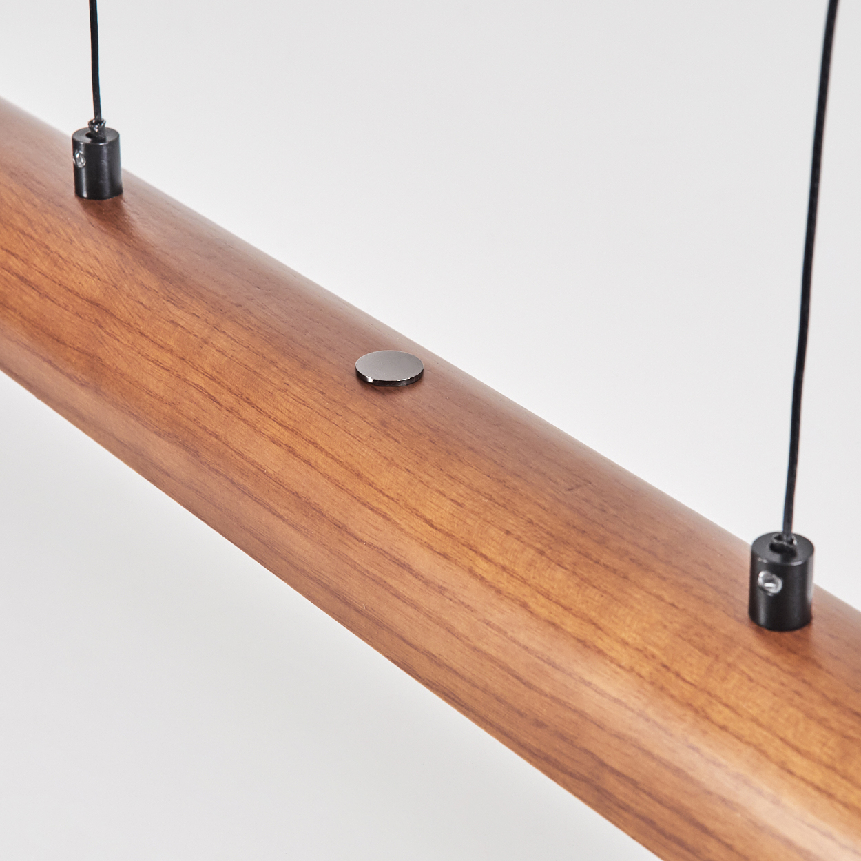 Nahaufnahme eines Holzbalkens mit zwei hängenden schwarzen Drähten und Metalldetails vor weißem Hintergrund.
