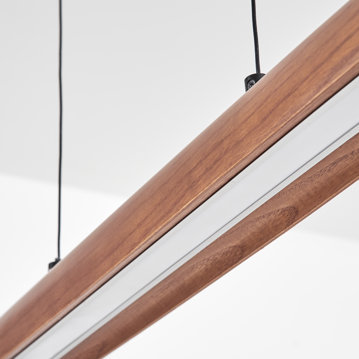 Nahaufnahme einer hölzernen Leuchte, angewinkelt. Sie hat einen weißen Lichtstreifen, schwarze Kabel und sitzt vor weißem Hintergrund.
