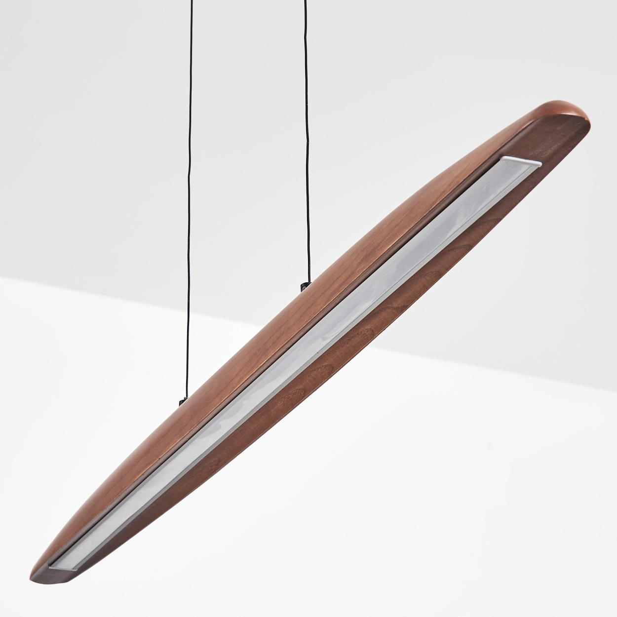 Eine moderne, längliche Pendelleuchte aus Holz mit einem silbernen Streifen. Sie hängt an zwei schwarzen Drähten vor weißem Hintergrund.