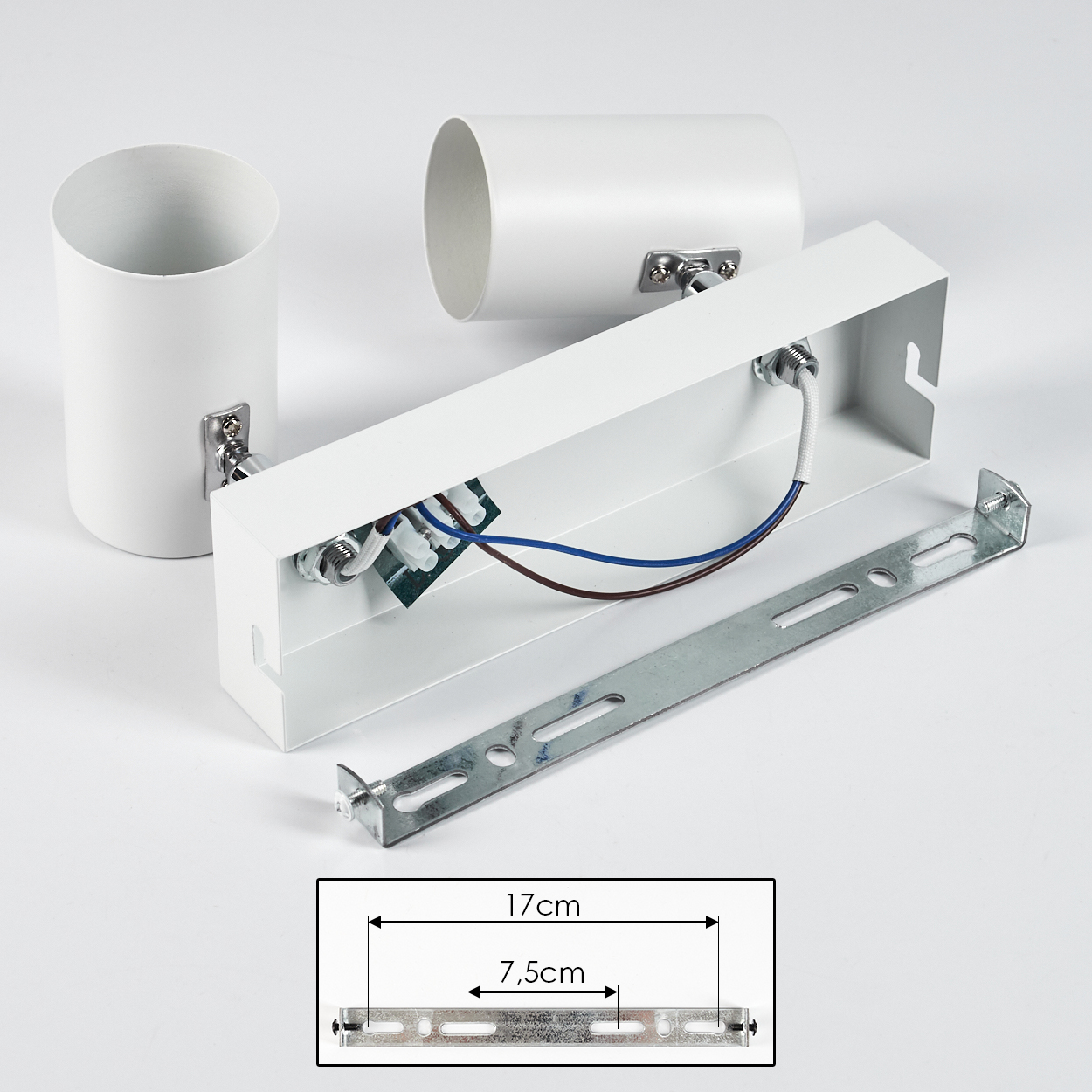 Weiße Deckenlichtkomponenten. Enthält zwei Zylinder, eine rechteckige Box, eine Metallhalterung und ein GrößenDiagramm. Drähte sichtbar.