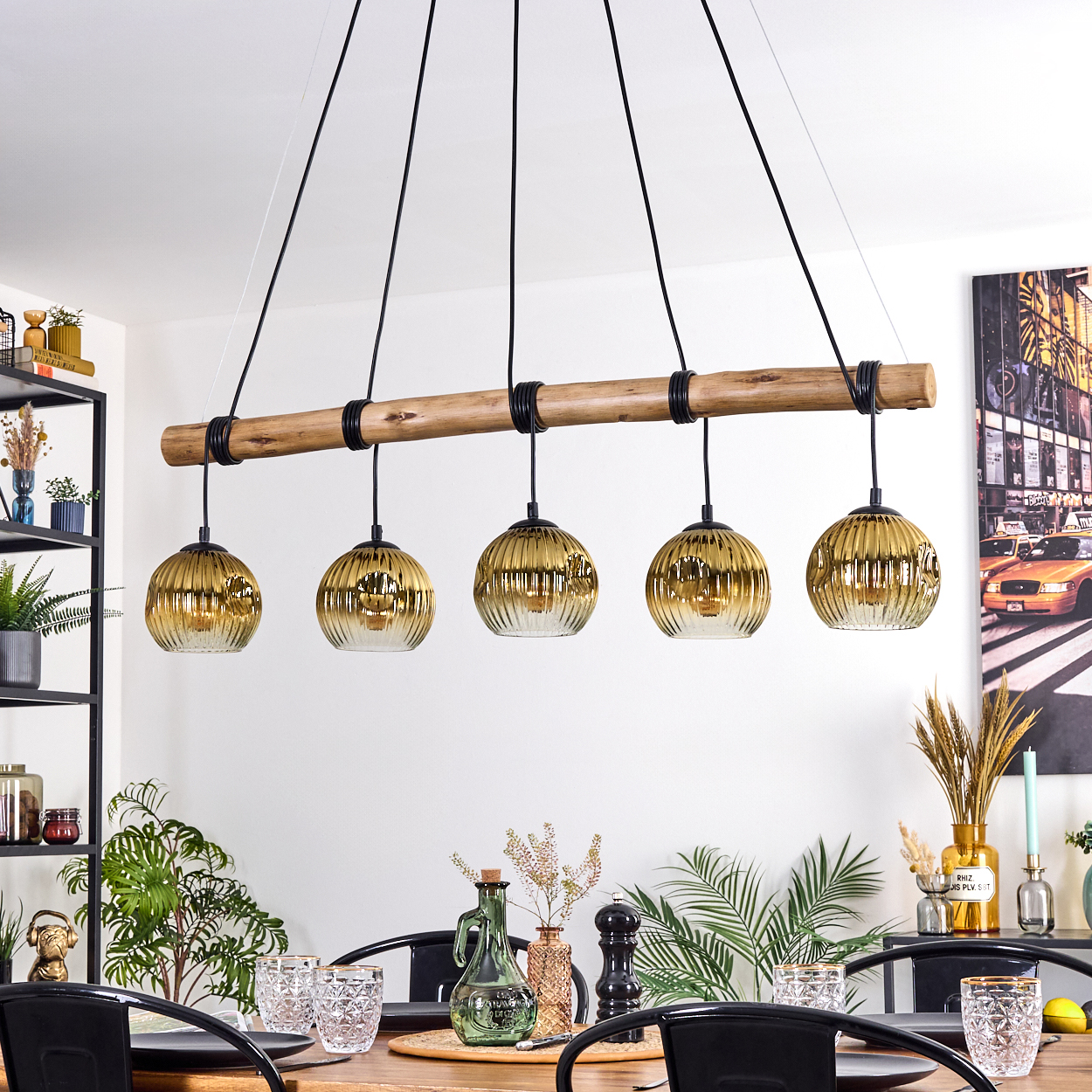 Esszimmer mit Holztisch, schwarzen Stühlen und einer Leuchte mit fünf goldfarbenen Kugellampen.