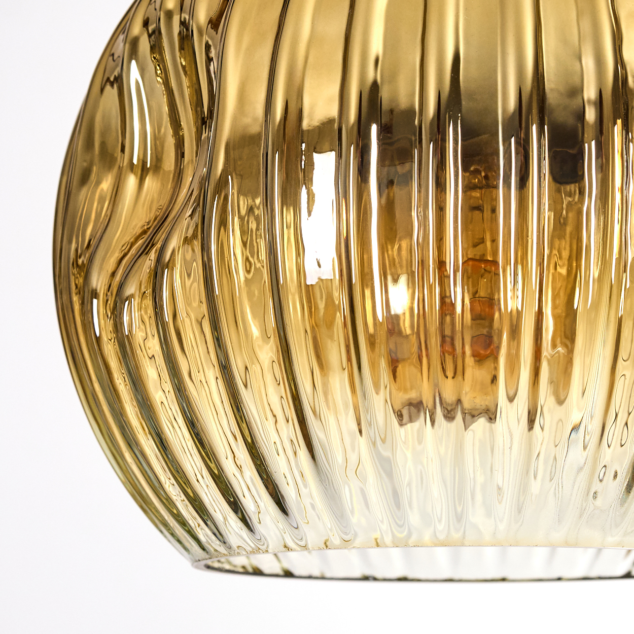 Nahaufnahme einer goldenen Glas-Hängeleuchte. Sie hat vertikale Rippen und eine Glühbirne im Inneren. Der Hintergrund ist weiß.
