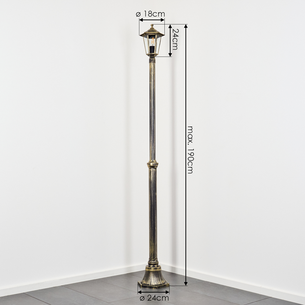 Dekorative Außenlaterne. Sie ist bronzefarben, hoch und steht vor einer weißen Wand. Abmessungen sind angegeben.