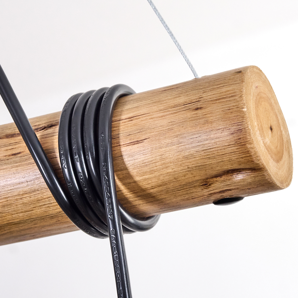 Ein Holzstamm mit schwarzen Drähten. Ein silbernes Kabel ist am Stamm befestigt. Der Hintergrund ist weiß.