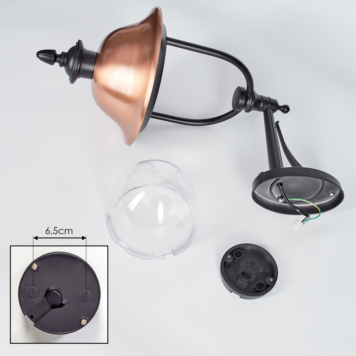 Eine zerlegte schwarze und kupferfarbene Außenlampe auf weißem Untergrund. Teile umfassen einen Schirm, eine Glasabdeckung und einen Sockel.