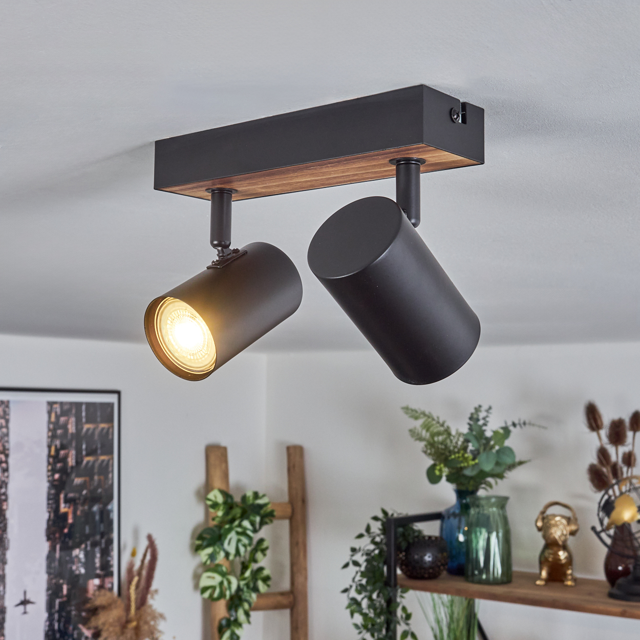Moderne Deckenleuchte mit zwei verstellbaren schwarzen Strahlern. Der Holzbalken und die Decke sind weiß.