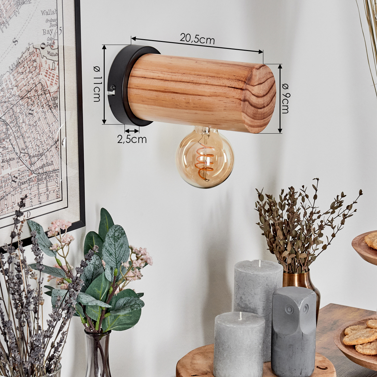 Eine hölzerne Wandlampe mit Glühbirne, neben Blumen, Kerzen und einer Karte.
