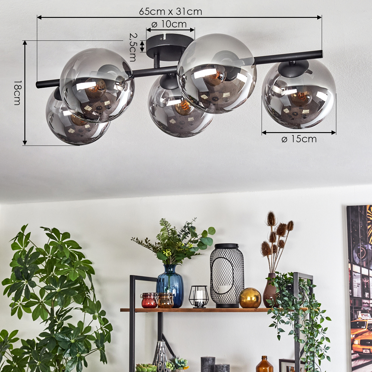 Eine moderne Deckenleuchte mit fünf kugelförmigen Glasschirmen, schwarzem Rahmen. Darunter ein Regal mit Pflanzen und Dekoration.