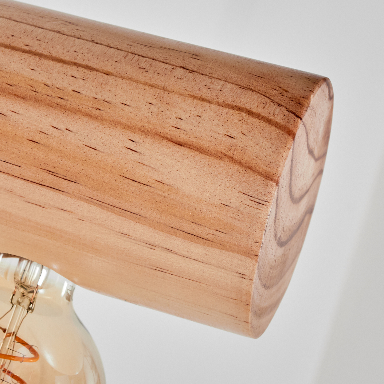 Nahaufnahme einer Holzlampenhalterung. Das Holz ist hellbraun mit sichtbarer Maserung. Darunter eine Glühbirne.