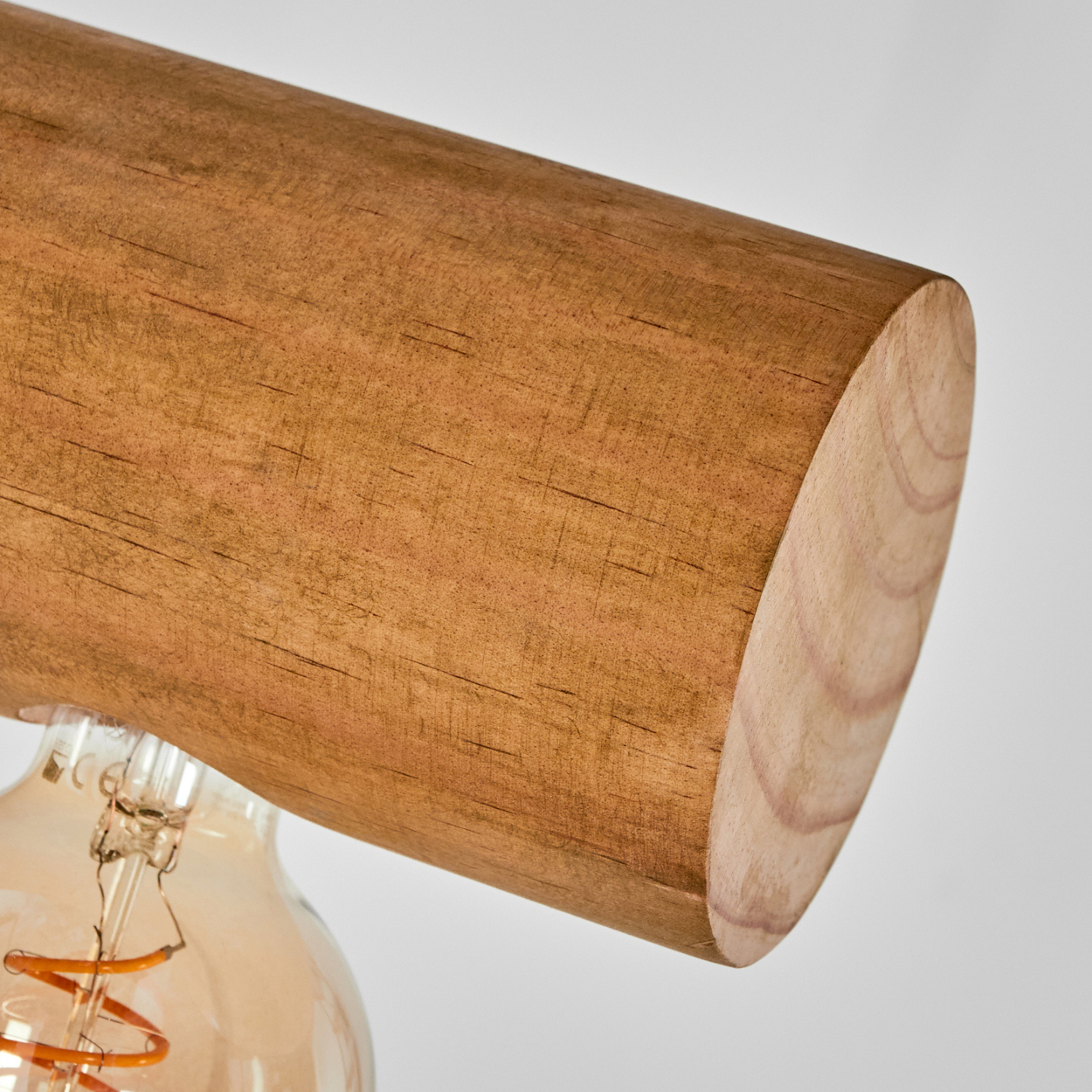 Nahaufnahme einer Holzleuchte. Über einer Vintage-Glühbirne befindet sich ein großer, brauner Holzbalken.