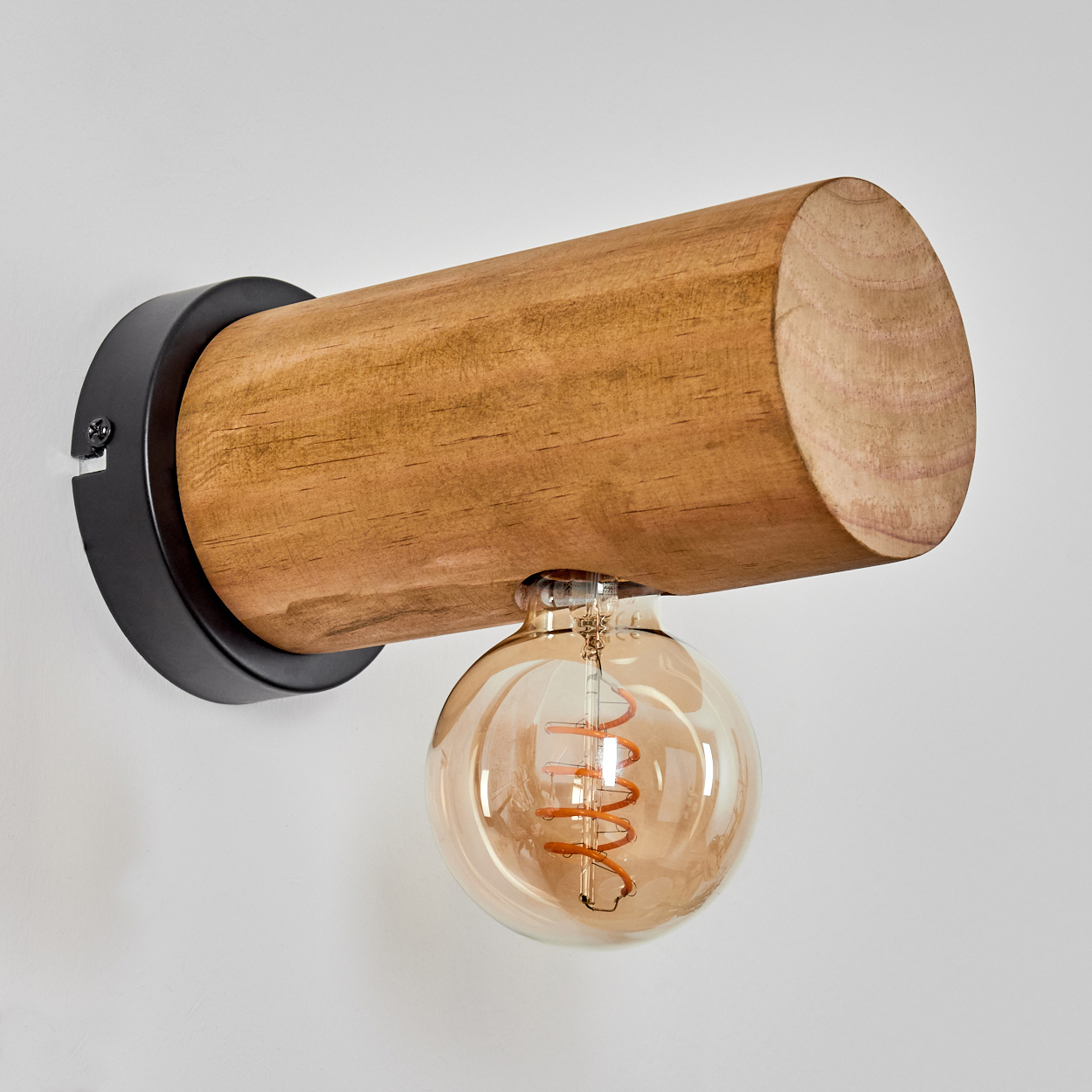 Eine Wandlampe aus Holzbalken mit einer kugelförmigen Glühbirne. Die Lampe ist an einer weißen Wand befestigt.