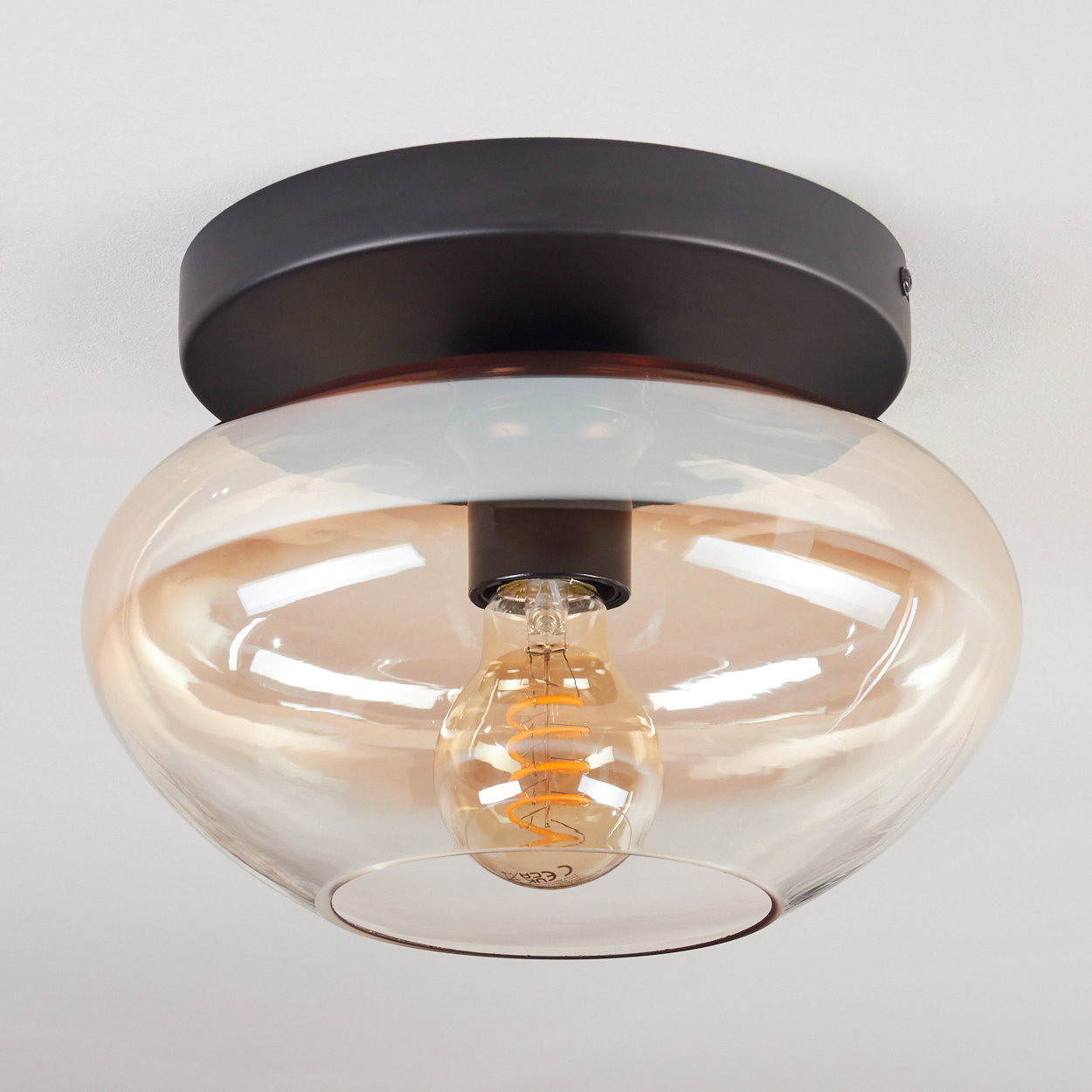 Eine Deckenleuchte mit Glaskugel und Edison-Glühbirne, vor weißem Hintergrund.