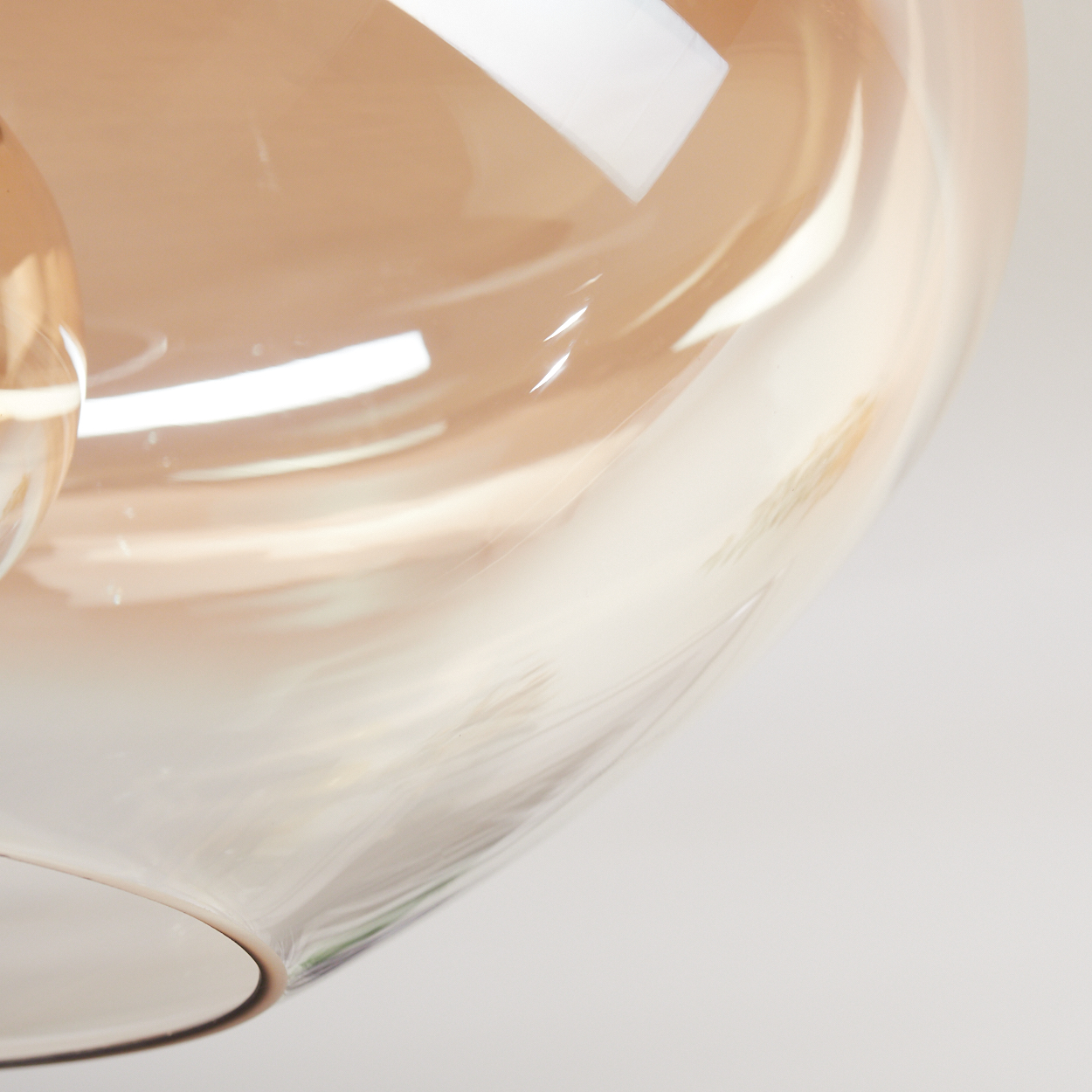 Nahaufnahme eines Glasobjekts. Das Glas hat einen hellbraunen Farbton und reflektiert Licht. Der Hintergrund ist weiß.