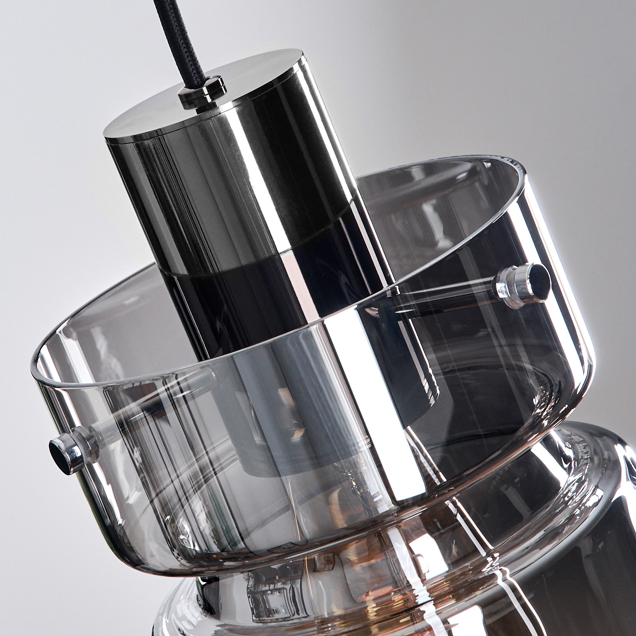 Eine moderne Hängeleuchte aus Glas und Metall. Ein zylindrisches Metallteil hängt in einer Glasschale, mit einem Kabel befestigt.