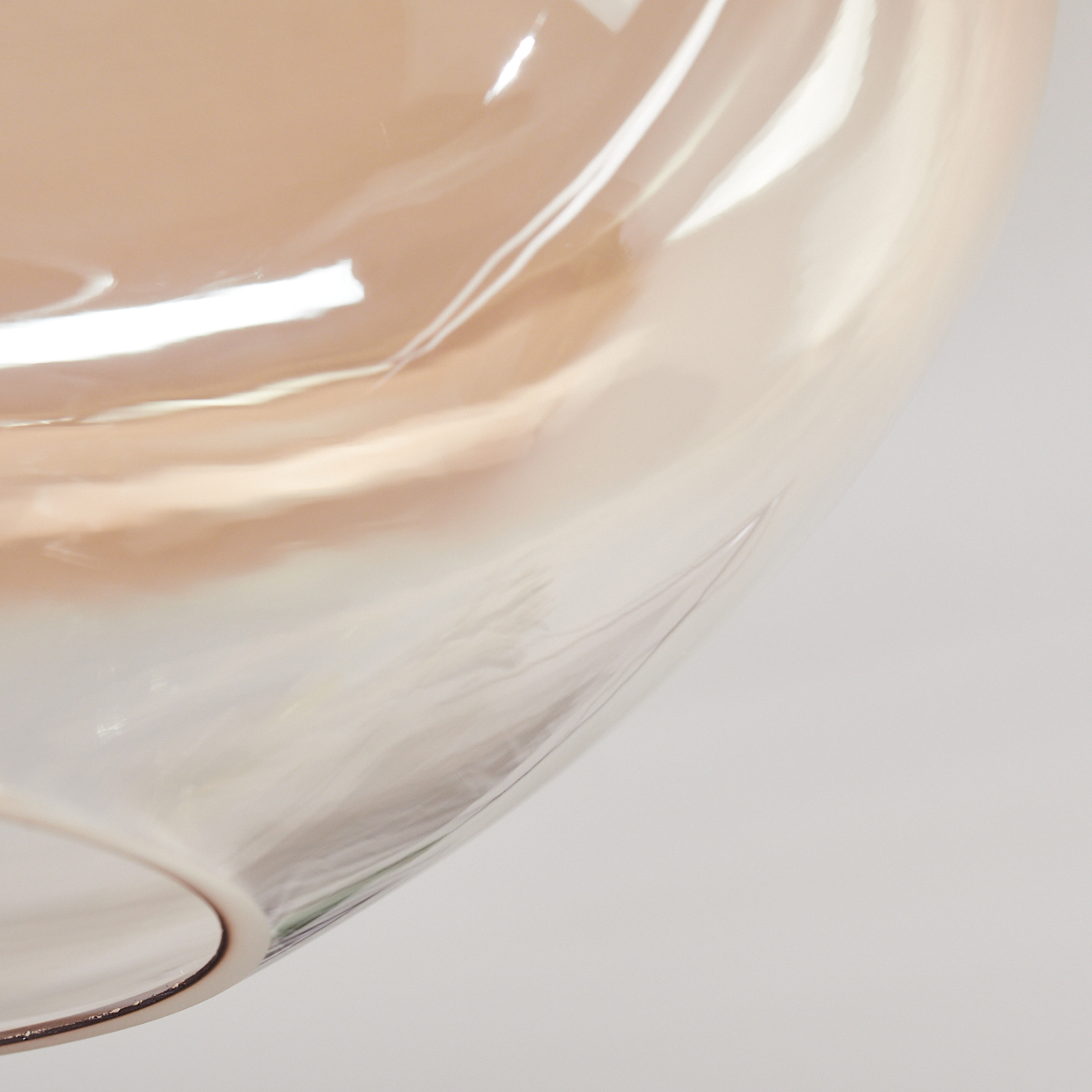 Nahaufnahme eines Glasobjekts. Das Glas ist transparent mit Pfirsich- und Weißtönen. Der Hintergrund ist schlicht weiß.
