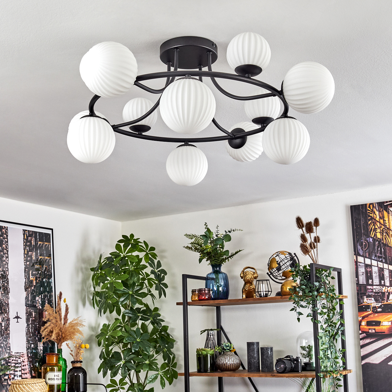 Moderne Deckenlampe mit weißen Kugellampen. Ein Raum mit Pflanzen und Dekorationen. Ein Regal mit verschiedenen Gegenständen und ein Bild an der Wand.
