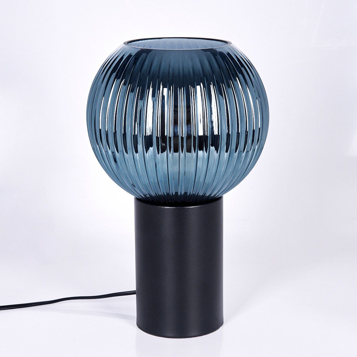 Eine moderne Lampe mit einer blauen, gerippten Glaskugel und einem schwarzen zylindrischen Sockel. Ein schwarzes Kabel erstreckt sich vom Sockel.