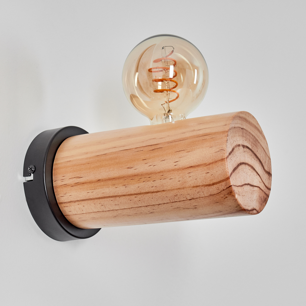 Eine Holzlampe mit Glühbirne. Die Lampe ist an einer weißen Wand befestigt. Die Birne ist rund und hat einen Wendelfaden.