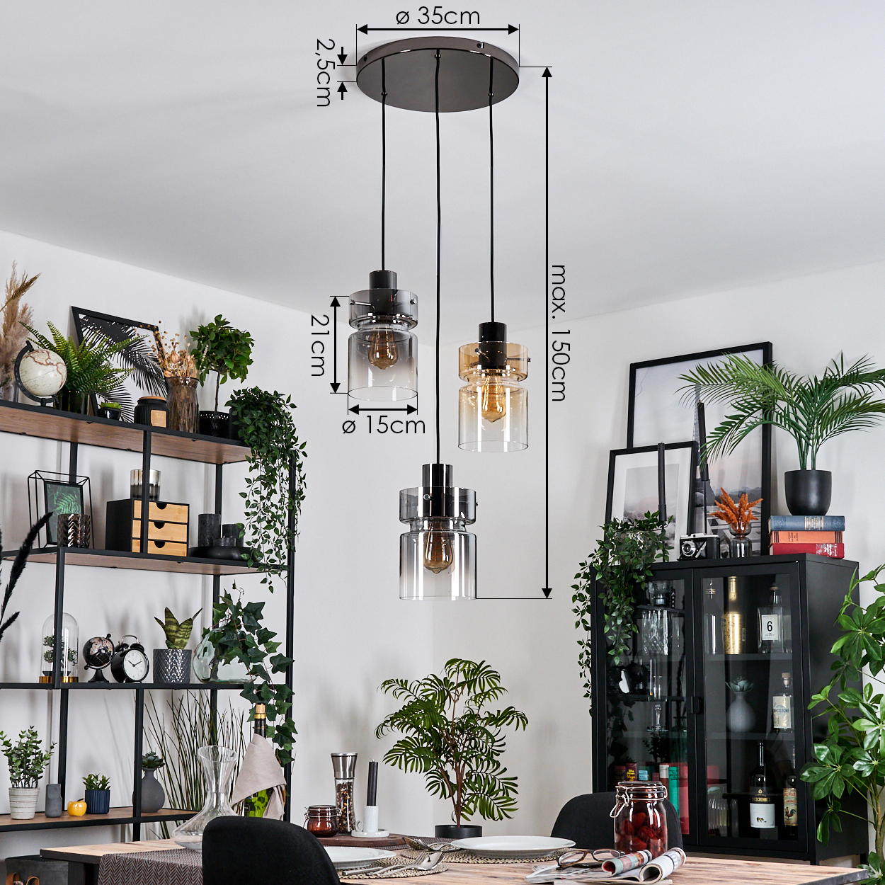 Drei Pendelleuchten hängen von der Decke. Ein Esstisch ist mit Tellern und Gläsern gedeckt. Regale beherbergen Pflanzen und Dekoration.